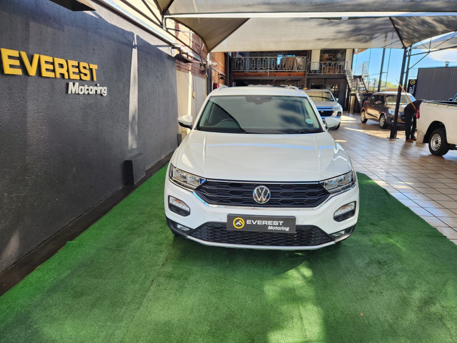 Front exterior view of the white 2021 Volkswagen T-Roc 1.4 TSI Design Auto parked inside the showroom.