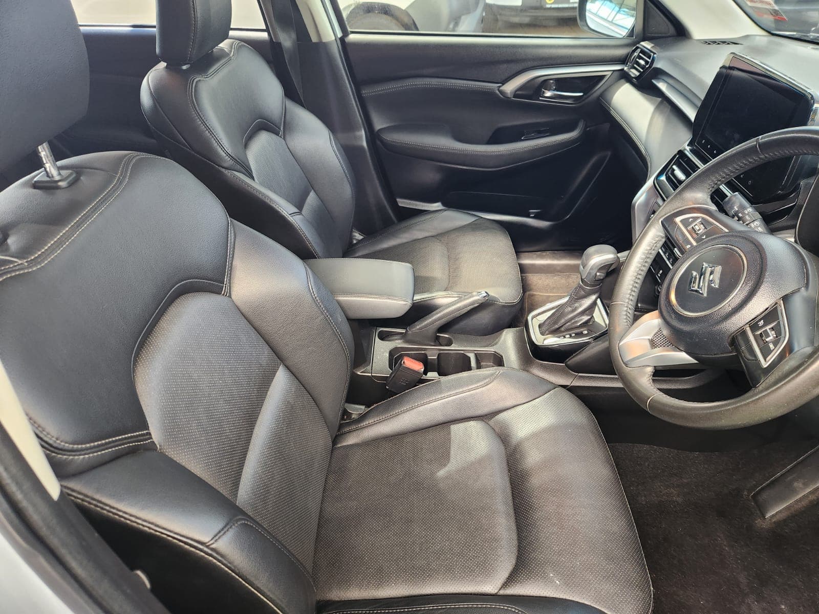 Driver's cockpit view of the 2024 Suzuki Grand Vitara 1.5 GLX Auto, showing controls and leather seat.