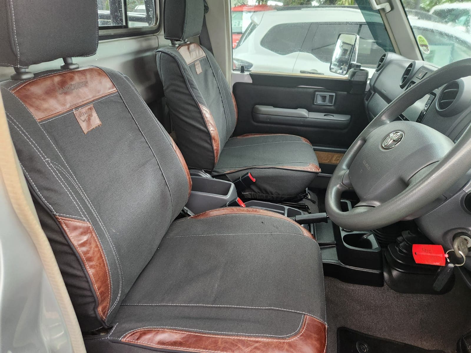 Interior front cabin view of the 2019 Toyota Land Cruiser 79 4.5 D Single-Cab, highlighting custom seat covers.